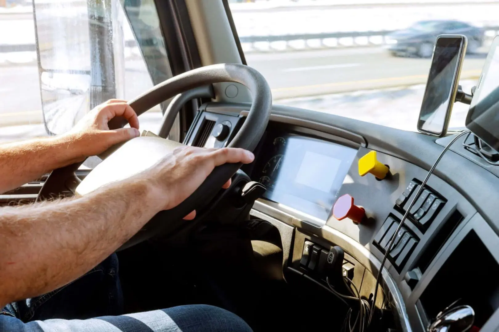 Driver's hands on steering wheel in truck.