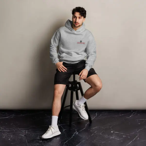 Man in grey hoodie and black shorts sitting on stool.