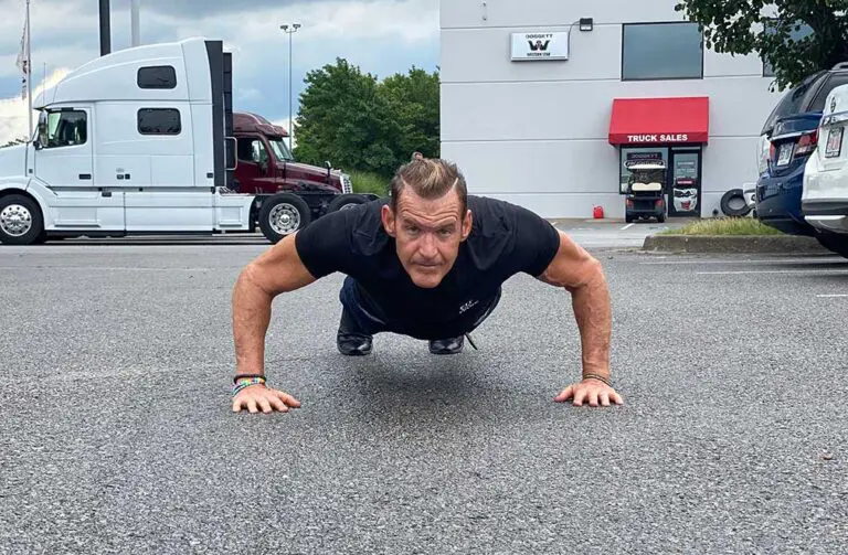 Man doing pushups in parking lot.