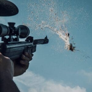 Person aiming rifle at target with splash.