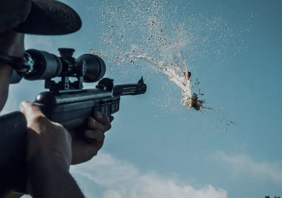 Person aiming rifle at target with splash.