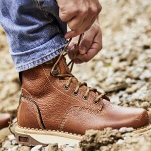 Person tying brown leather work boots.