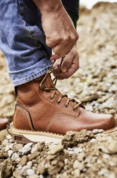 Person tying brown leather work boots.