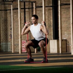 Man doing squats with resistance band.