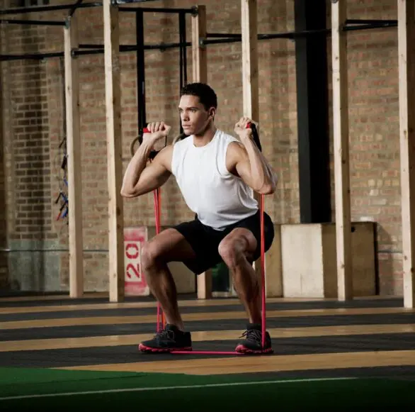 Man doing squats with resistance band.