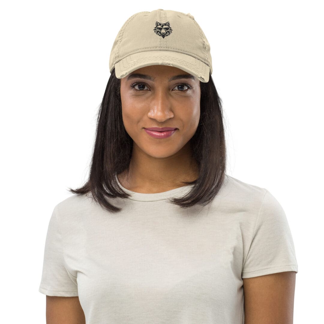 Woman wearing a tan distressed cap with a wolf logo.