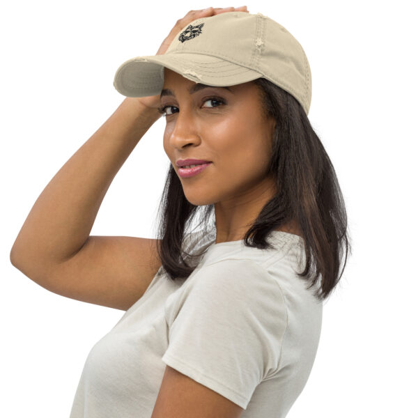 Woman wearing a beige cap with wolf logo.