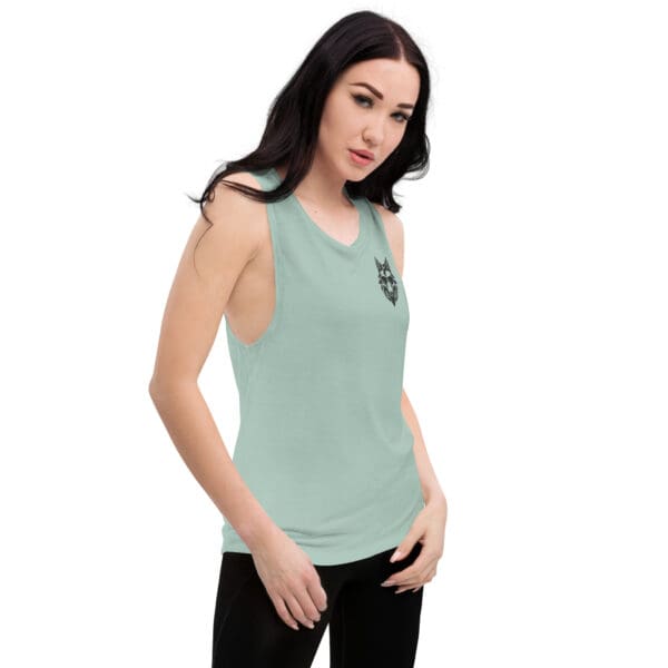 Woman wearing a light green tank top with a wolf logo.