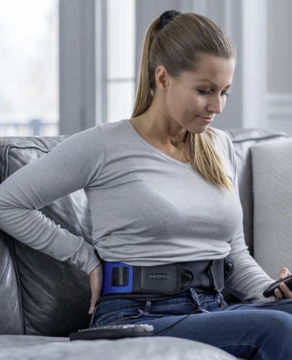 Woman wearing a back support on a couch.